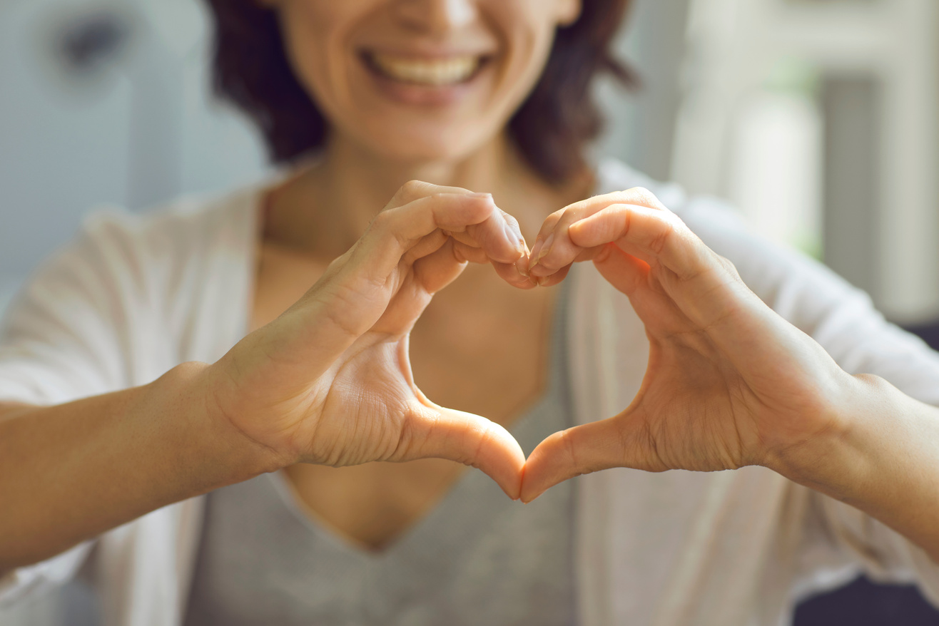 Cropped Shallow Focus Image of Happy Smiling Lady Showing Heart Symbol with Her Hands